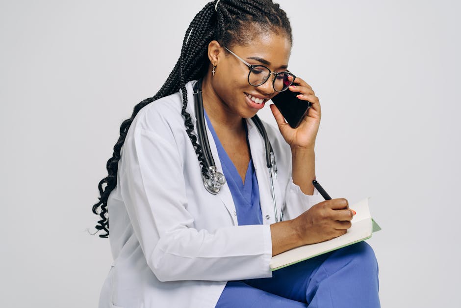 Female doctor smiling while talking on the phone and taking notes, wearing a stethoscope.