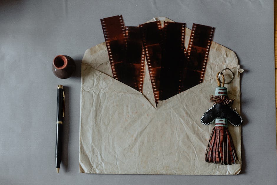 Flat lay of vintage film strips, an envelope, and rustic keychain on a textured surface.